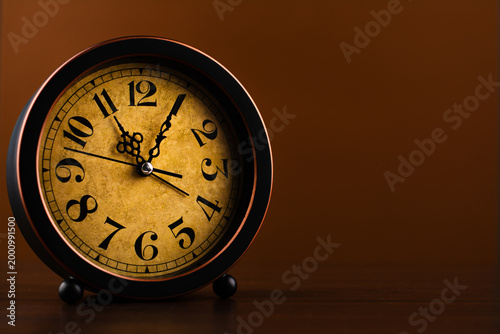 Vintage clock photographed against a brown background, conveying the concept of punctuality and work.