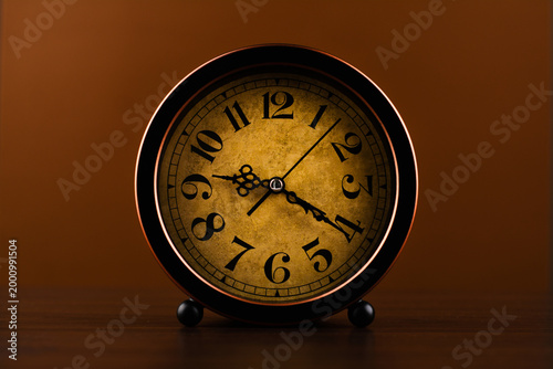Vintage clock photographed against a brown background, conveying the concept of punctuality and work.