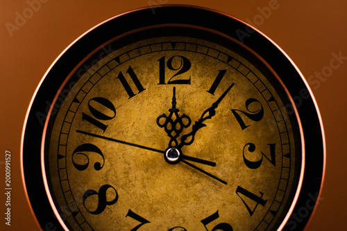 Vintage clock photographed against a brown background, conveying the concept of punctuality and work.