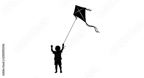 Silhouette of a happy young child flying a kite.