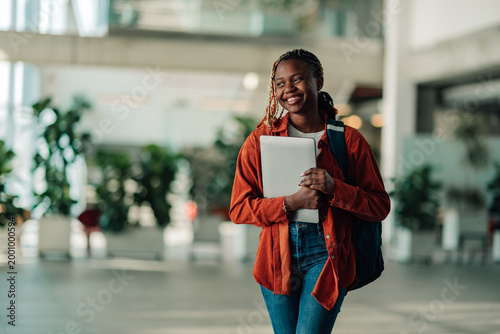 Canvastavla African american female student confidently walking on university campus, carryi