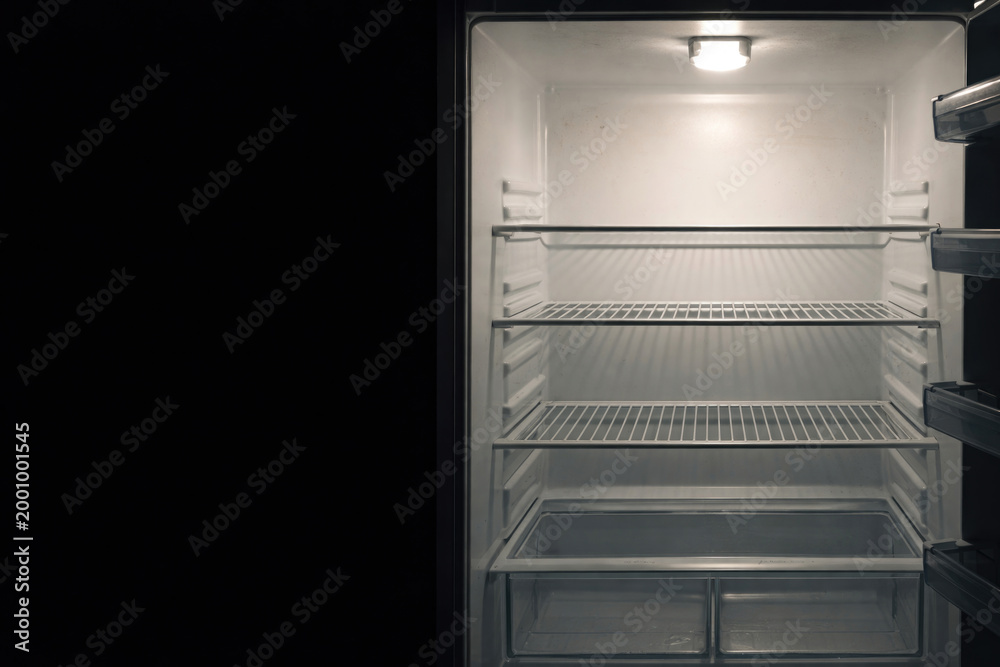 Fototapeta premium An empty open refrigerator with lighting inside. Space for text.