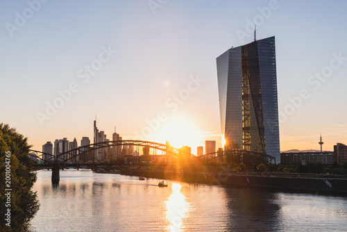Moderne Banken-Architektur am Fluss bei Sonnenuntergang mit Stadtsilhouette und Hochhaus in Frankfurt