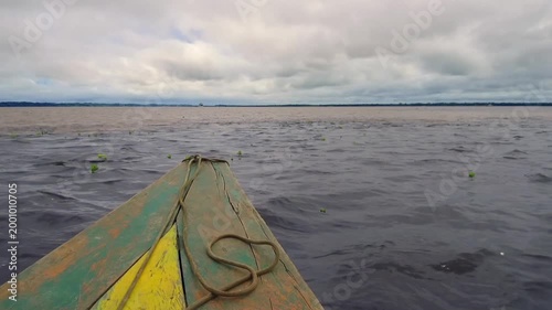 Point of view from wooden boat moving on Amazon River with water and cloudy sky