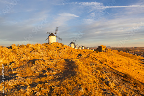 Consuegra windmills lining a golden La Mancha hill at sunset