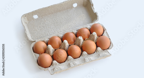 Expensive eggs. Eggs in an open cardboard box, a gold chain on top. Conceptual image, rising food prices, inflation, economic crisis