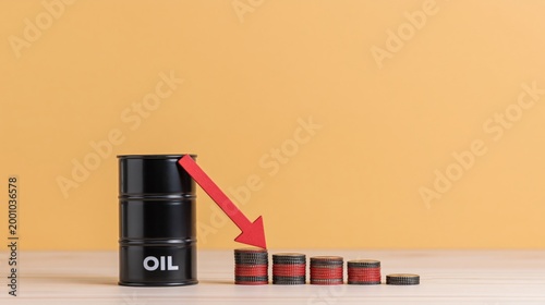 Oil barrel and stacked coins showing price decline on table
