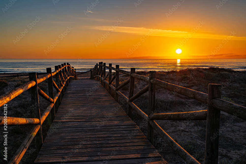 Obraz premium amanecer-playa-pasarela-madera.jpg.