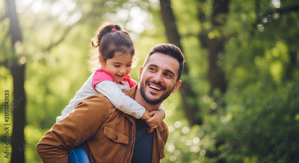Fototapeta premium A joyful father carries his young daughter on his shoulders through a lush green forest creating a heartwarming family moment