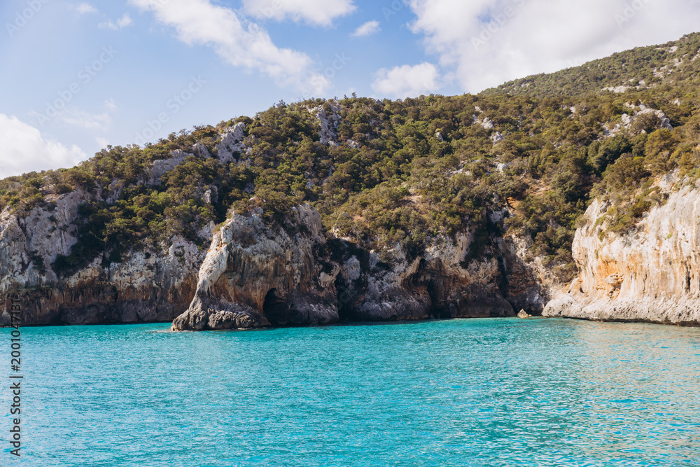 Obraz premium Cala Luna beach with turquoise water and dramatic cliffs in the Gulf of Orosei, Sardinia, Italy, during summer