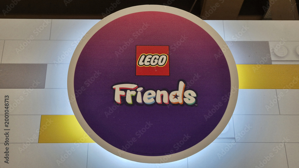 Fototapeta premium A circular purple and pink gradient LEGO Friends logo sign with backlighting, centered on a white brick-patterned surface. Picture taken in April 27, 2026 in Bucharest, Romania.