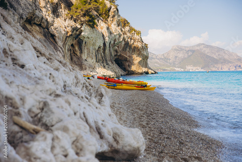 Tableau sur toile Colorful kayaks resting on the pebble beach of Cala Luna, Sardinia, Italy, with