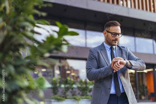 Foto Businessman Checking Watch Outside Modern Office Building While Waiting For Meet