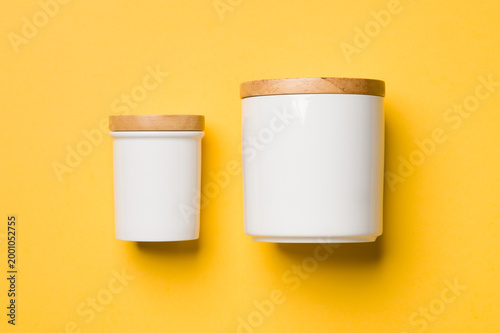 White ceramic kitchen canisters with wooden lids on a yellow background