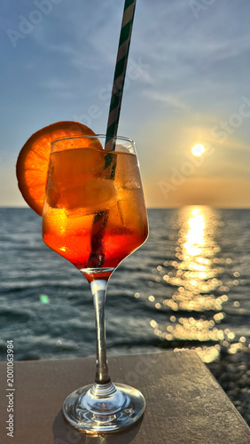 Spritz Veneziano glass with orange slice on seaside table at golden sunset glow