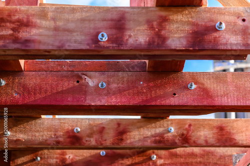 Close-up of roof frame with fire-retardant treated wooden beams and metal bolts, showing protective coating, structural detail and roofing construction under natural light