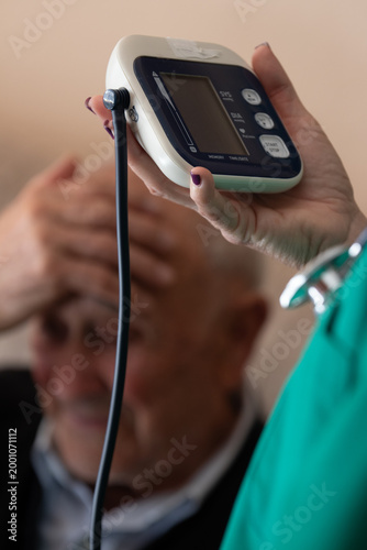 Принти на полотні nurse holding digital blood pressure monitor while elderly patient looks worried