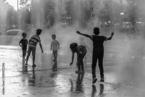 Vienne (Autriche, Europe) - Vue monochrome de jeux d'eau d'un groupe d'enfants sur la place Praterstern à la tombée de la nuit en été