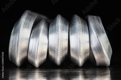 Bent aluminum rods placed on a metal surface in an industrial setting. Malleability and lightness of nonferrous metals used as raw materials in the metallurgical and manufacturing industries