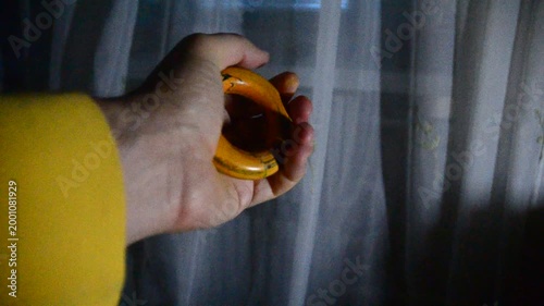 Man in a dark room doing sports wringing out hand expander hands visible object of movement hand holding a glass of wine