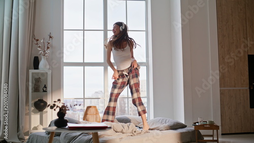 Photos Joyful woman jumping bed home