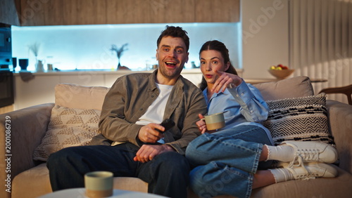 Relaxed lovers watching movie switching channels at late home. Couple looking tv