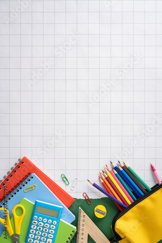 Back to school vertical supplies layout with colored pencils, notebooks, calculator and ruler on graph paper