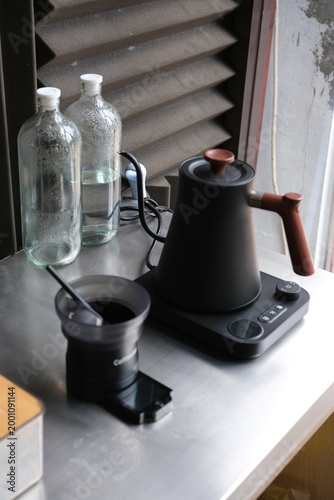 coffee maker and kettle on a metal countertop by a window
