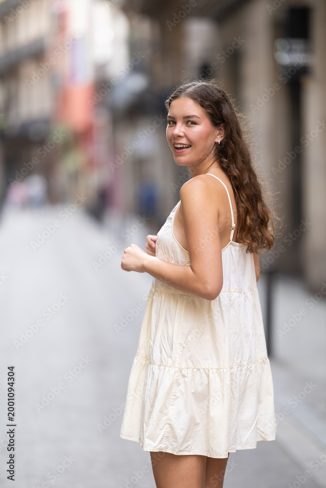 Fototapeta premium Young woman in white dress walking along the streets of the historical center of the city
