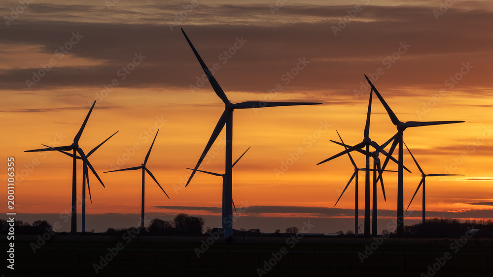 Fototapeta premium Windräder in einem Windpark bei Struckum nahe der Nordsee in Nordfriesland, Schleswig-Holstein, Deutschland bei Sonnenuntergang.