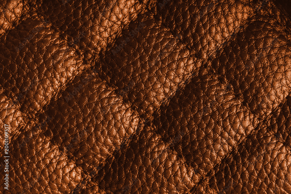 Obraz premium Close up, macro of orange quilted leather texture with stitched diamond pattern, luxury material surface shining metal effect for fashion, upholstery or design wallpaper, rough, relief background