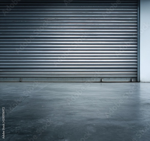 Industrial metallic roller door against a textured concrete floor