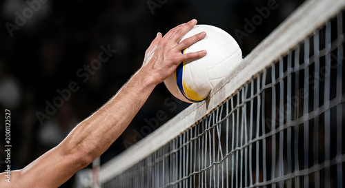 Close-up of a volleyball player hand blocking the ball above the net during an intense indoor match competition.