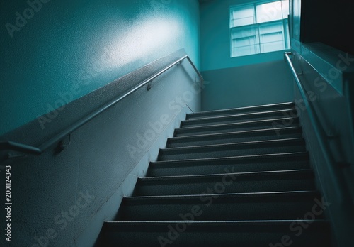 Narrow concrete stairs ascend towards a light-filled window, illuminated by cool blue light