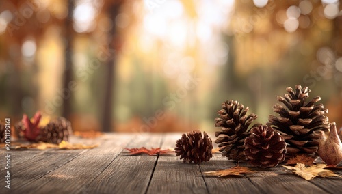 Rustic wooden table with scattered pinecones and autumn leaves