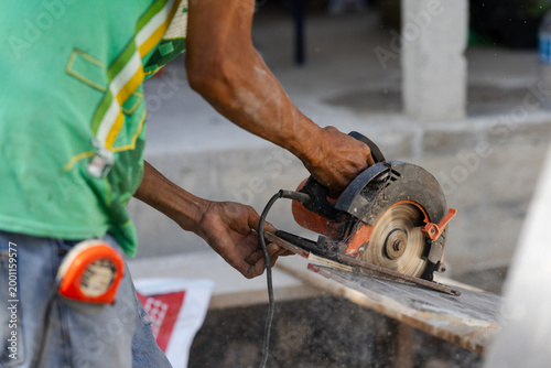 Construction worker cutting tile with angle grinder producing dust and sparks