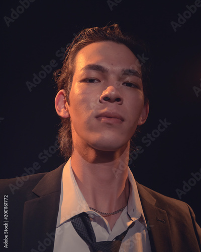 A young man in a suit captures an introspective moment under soft lighting, showcasing a blend of seriousness and tranquility that resonates with artistic elegance.
