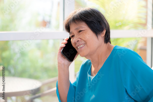 Free Download Senior asian woman telephone smiling and relax sitting on sofa in living room at home, cheerful elderly woman talking with smart phone sitting on couch in home, lifestyle and communication. - GFXLoad
