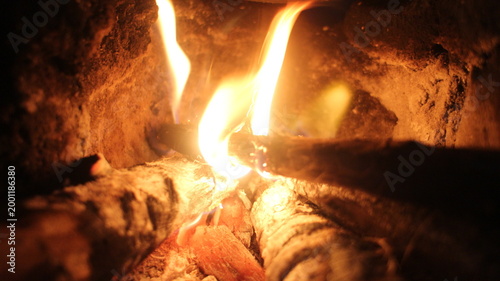 Close up of burning wood logs blazing in flames inside black wrought iron wood burning fire.