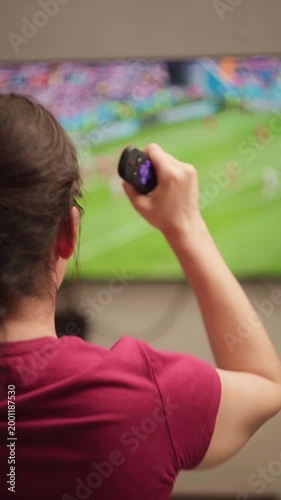 Excited female fan celebrating a goal while watching a soccer match on television, showing intense emotion and passion for her favorite team during a live championship broadcast