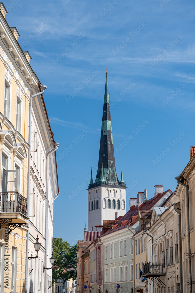 Fototapeta premium Church steeple towers over pastel colored buildings in Tallinn Estonia