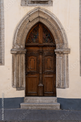 Carved old wooden door inside a stone arch along the street in Tallinn Estonia