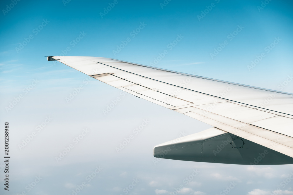Fototapeta premium Airplane wing flying high in blue sky clouds