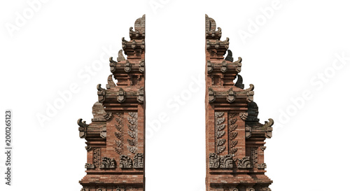 Ornate Balinese gate with intricate carvings and brickwork against a dark backdrop featuring traditional temple architecture and cultural heritage