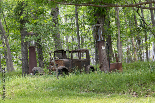 Old rusty car and fuel pump in the woods