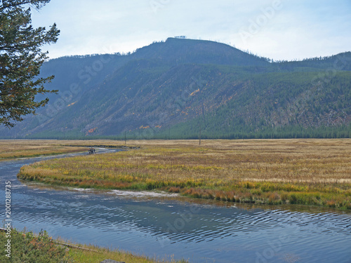 Yellowstone National Park autumn scenery with Firehole River and yellow dry grass field on sunny day