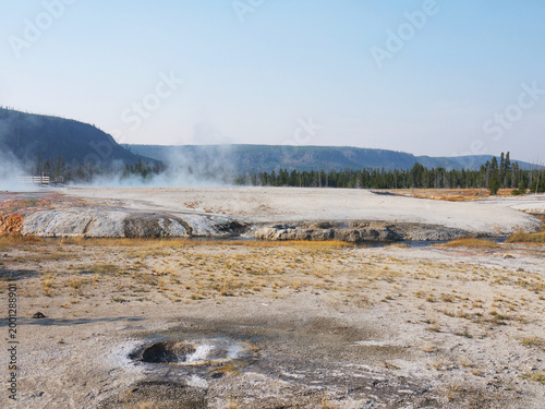 Iron Spring creek in volcanic landscape with geysers, fumaroles and yellow dry grass in Yellowstone