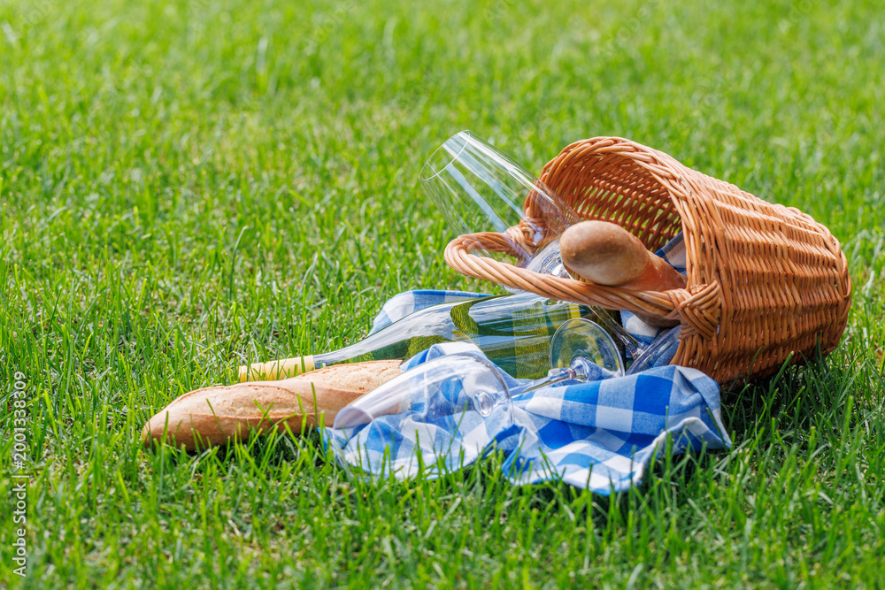 Obraz premium Picnic basket with wine, grapes, and baguette
