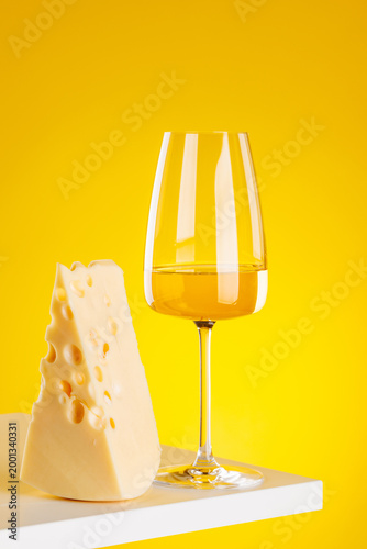 Glass of white wine with cheese on yellow background food pairing concept