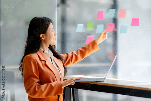 Foto Businesswoman organizing creative ideas on a glass wall during a planning meetin